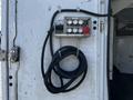 Control panel with multiple switches and a red button mounted on a wall with a coiled black cable hanging down