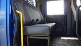 A blue interior of a 2012 International DuraStar 4300 featuring a gray bench seat with seatbelts and an adjacent structure for driver support