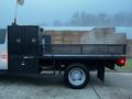 A 2015 Ford F-550 flatbed truck with a black service body and storage compartments on the side