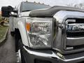 A 2013 Ford F-350 SD with a shiny chrome grille and headlights visible in the foreground featuring multiple amber lights on the roof