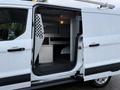 A 2017 Ford Transit Connect with an open side door revealing a customized interior featuring shelving and storage compartments