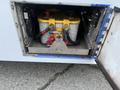 A compartment of a 2017 Chevrolet Express displaying two batteries connected with cables and a yellow cap on top