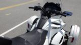 A white 2013 Can-Am Spyder motorcycle with a black seat and handlebars visible in the foreground