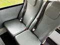 Two gray upholstered seats with seatbelts in a vehicle interior designed for passengers