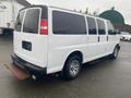 A white 2012 Chevrolet Express van with chrome wheels parked on a surface, showing its side and rear view