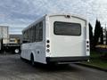 A white 2015 Chevrolet Express with multiple windows and a rear license plate visible parked at an industrial location