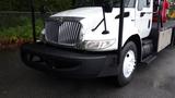 A white 2010 International 4300 truck with a chrome grille and a flatbed, featuring distinct headlights and a black grille guard