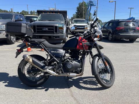 A 2022 Royal Enfield Himalayan motorcycle featuring a black body with red accents and a side box on the rear wheel