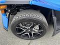 Close-up of a black alloy wheel with a multi-spoke design mounted on a wide tire of a blue 2020 Polaris SlingShot