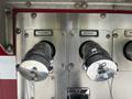 Two discharge valves labeled Discharge 1 and Discharge 2 on a metal panel of a 2006 Emergency One Fire Truck