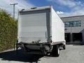 A 2021 Hino 338 box truck with a white exterior and a closed rear compartment is parked, showcasing its large cargo area and rear hitch attachment