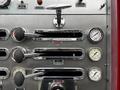 A close-up of the control panel of a 1991 Sutphen Deluge featuring chrome levers and gauges labeled for hosebed and engine functions