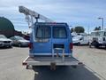 A blue 2009 Ford Econoline van with a utility ladder attached to the top and a rear step bumper visible
