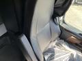 A black driver's seat of a 2022 Freightliner Cascadia with plastic covering and an armrest