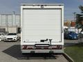 A 2023 Ford E-450 box truck viewed from the rear with a white exterior and a loading dock bumper but no visible logos or markings