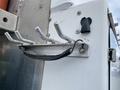 Close-up of a metal rack with multiple hooks mounted on a vehicle side, designed for holding tools or equipment