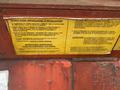 A yellow and black installation instructions label attached to a red metal surface with details about electrical connection and equipment installation