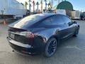 A black 2019 Tesla Model 3 with sleek lines and tinted windows parked with its rear facing the viewer