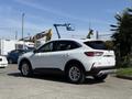 A 2020 Ford Escape parked in the foreground featuring a white exterior with a sleek design and alloy wheels