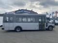 A gray 2016 Chevrolet Express bus with large windows and a side entrance door