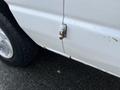 A 2008 Ford Econoline van showing signs of rust on the side and a damaged door latch