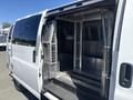 A 2007 Chevrolet Express van with an open side door revealing a spacious, empty interior featuring metal mesh partitions and a rubber floor mat