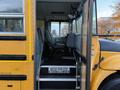 Interior of a yellow 2014 International 4300 school bus showing driver's seat and steps with a warning sign reading WATCH YOUR STEP ATTENTION A LA MARCHE