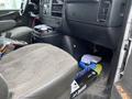 A 2014 GMC Savana interior showing the driver's side with a gray fabric seat and a cluttered floor with various items scattered around