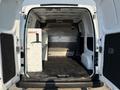 Interior of a 2021 Nissan NV200 cargo van with a clean, empty space featuring a white shelving unit on one side and a flat floor