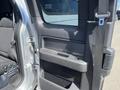 A 2014 Ford F-150 door interior featuring a black handle and window controls with a fabric seat visible in the background