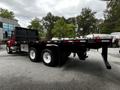 A red 2011 International 4400 truck with a flatbed design and dual rear wheels is shown from the side with an open flatbed and black side panels