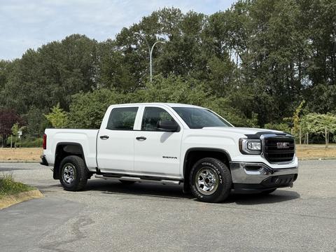 A white 2016 GMC Sierra 1500 pickup truck is parked with a crew cab and chrome accents on the front grille and wheels