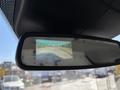 Rearview mirror display showing a backup camera view of a clear road with lane markings and surrounding landscape
