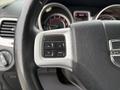 Close-up of the steering wheel of a 2013 Dodge Journey featuring control buttons for navigation and a textured black grip