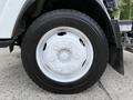 A silver wheel with a white hubcap mounted on a black tire from a 2017 Isuzu NPR HD truck