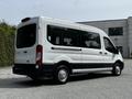 A white 2022 Ford Transit van is positioned at an angle showing its side and rear with large windows and sliding side doors
