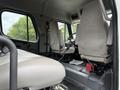 Interior view of a 2005 Freightliner M2 106 showing two grey upholstered seats and the dashboard area with a steering wheel and controls