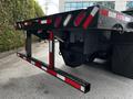 A black 2011 International 4400 truck with a flatbed and reflective striping on the edges is parked showing the rear chassis and tail lights