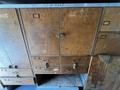 A wooden cabinet with multiple drawers and a central double door featuring ornate handles and a wood grain texture