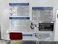 A 2016 Isuzu NQR featuring various instruction and safety warning labels related to operating the liftgate