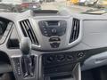 Interior view of a 2017 Ford Transit dashboard featuring a digital display center console and gear shift with controls for climate and audio functions