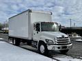 A 2019 Hino 338 24 foot cube truck in white with a large cargo box and distinctive front grille parked on a snowy road