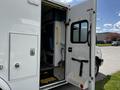 A 2013 Chevrolet Express with an open side door revealing interior seating and a step entrance