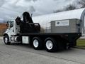 A white 2006 Freightliner M2 112 truck with a flatbed and a hydraulic lift on the back parked on a street