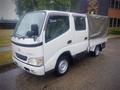 A white 2003 Toyota Toyoace truck with a covered cargo area and a flatbed design