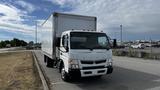 A white 2018 Mitsubishi Fuso FE truck with a box cargo body parked on a paved area