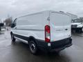 A 2018 Ford Transit van in white with a black lower section viewed from the rear angle