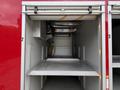 An empty storage compartment of a 2007 Ford F-550 with metallic shelves and a rolling door mechanism