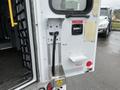A rear door of a 2016 Chevrolet Express with a metal handle pushbar an emergency release and a panel for locks and switches