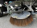 A 2012 Autocar Xpert featuring a large round street sweeper brush with long bristles attached to a mechanical arm and various connected hoses and components